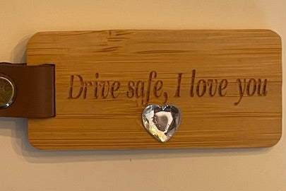 Wooden keychain with engraved text and a heart-shaped accent