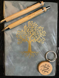 Two wooden pens and a keychain with a tree design on a gray surface.
