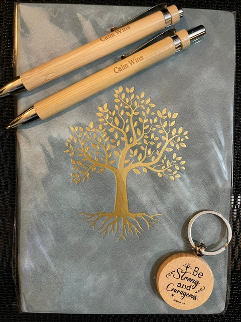 Two wooden pens and a keychain with a tree design on a gray surface.