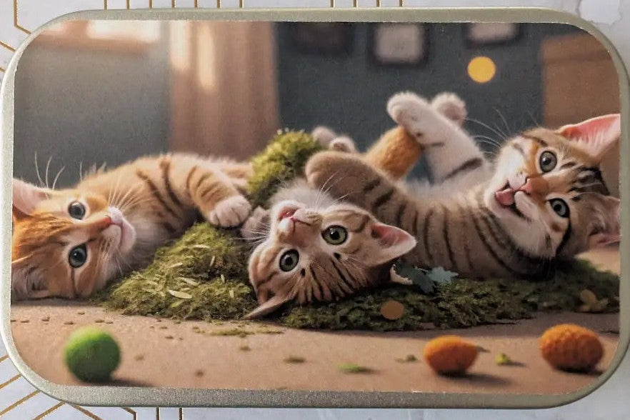 A rectangular mouse pad with rounded corners featuring a printed illustration of three playful orange tabby kittens on a mossy mat, shown on a light patterned surface.