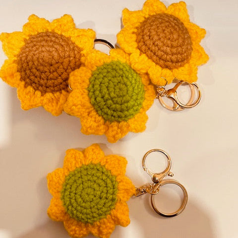 Three sunflower-shaped keychains on a light surface