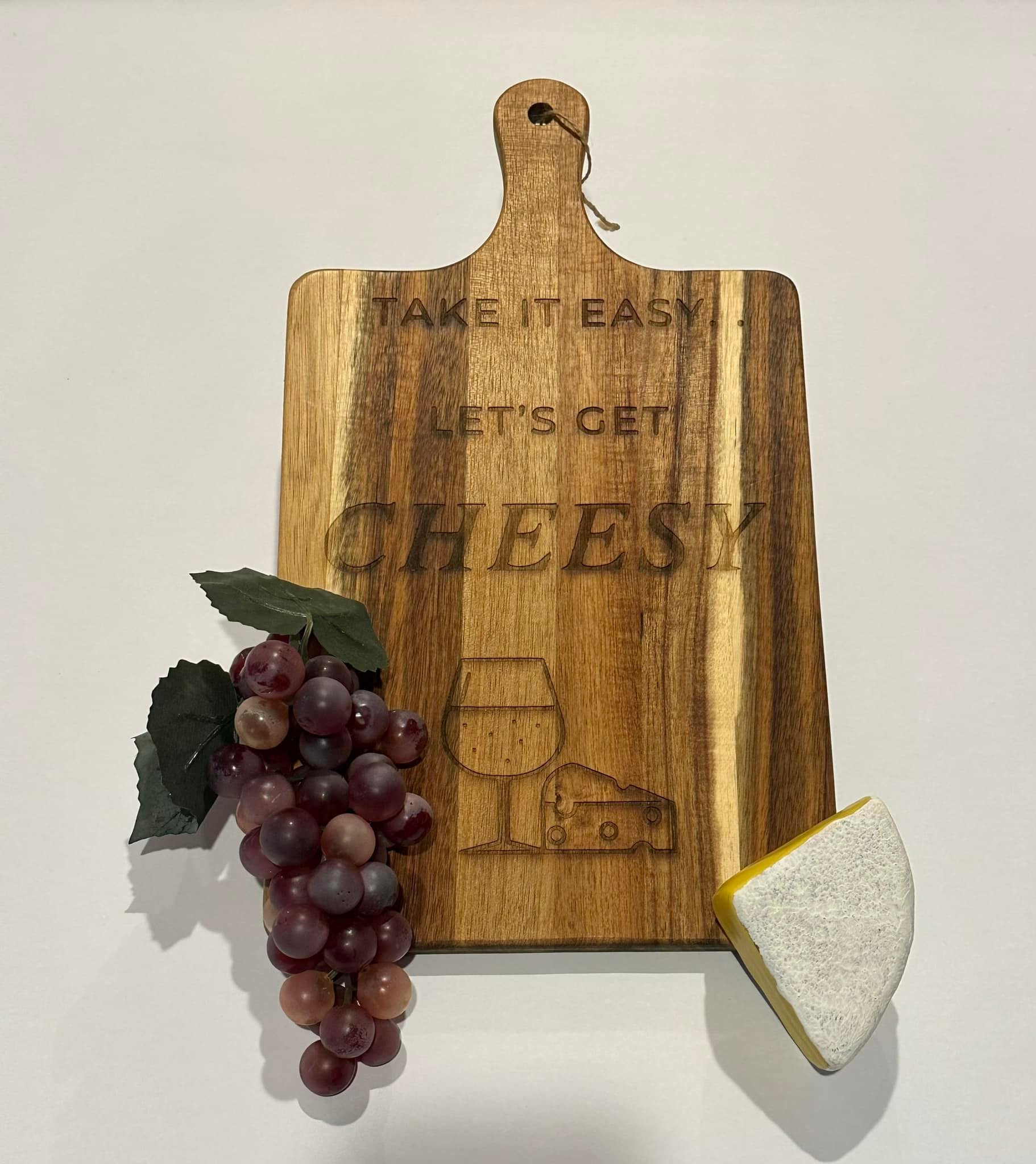 Wooden cutting board with 'Take it easy, let's get cheesy' text engraved