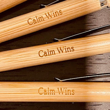 Set of wooden utensils with 'Calm Wins' engraving on a dark surface