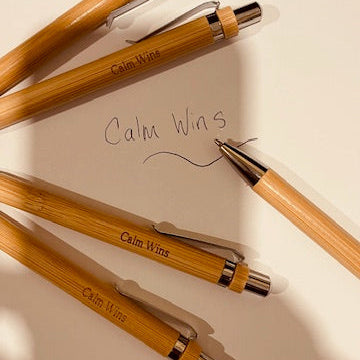 Bamboo pens with 'Calm Wins' engraving on a light surface.